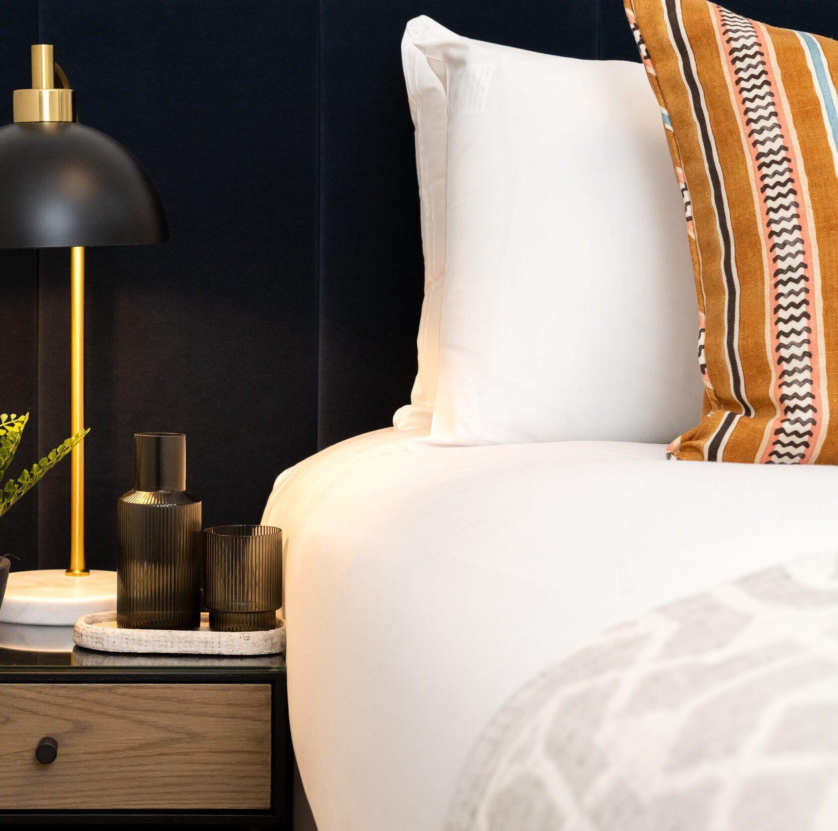 Close up of bedside lamp next to well presented bed