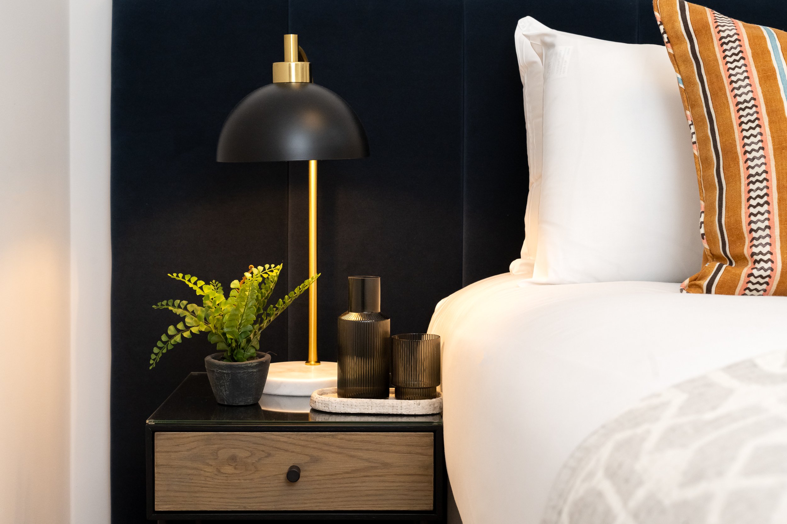 Close up of bedside lamp next to well presented bed