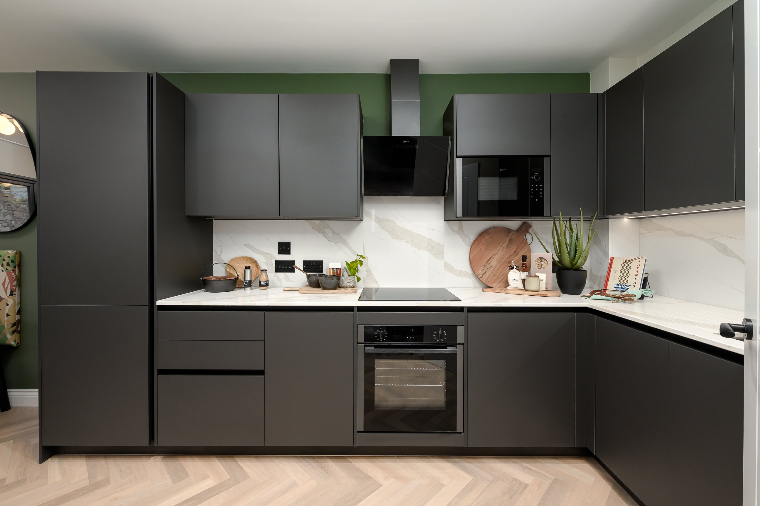 A modern kitchen featuring sleek black cabinets and vibrant green walls, creating a stylish and contemporary atmosphere.